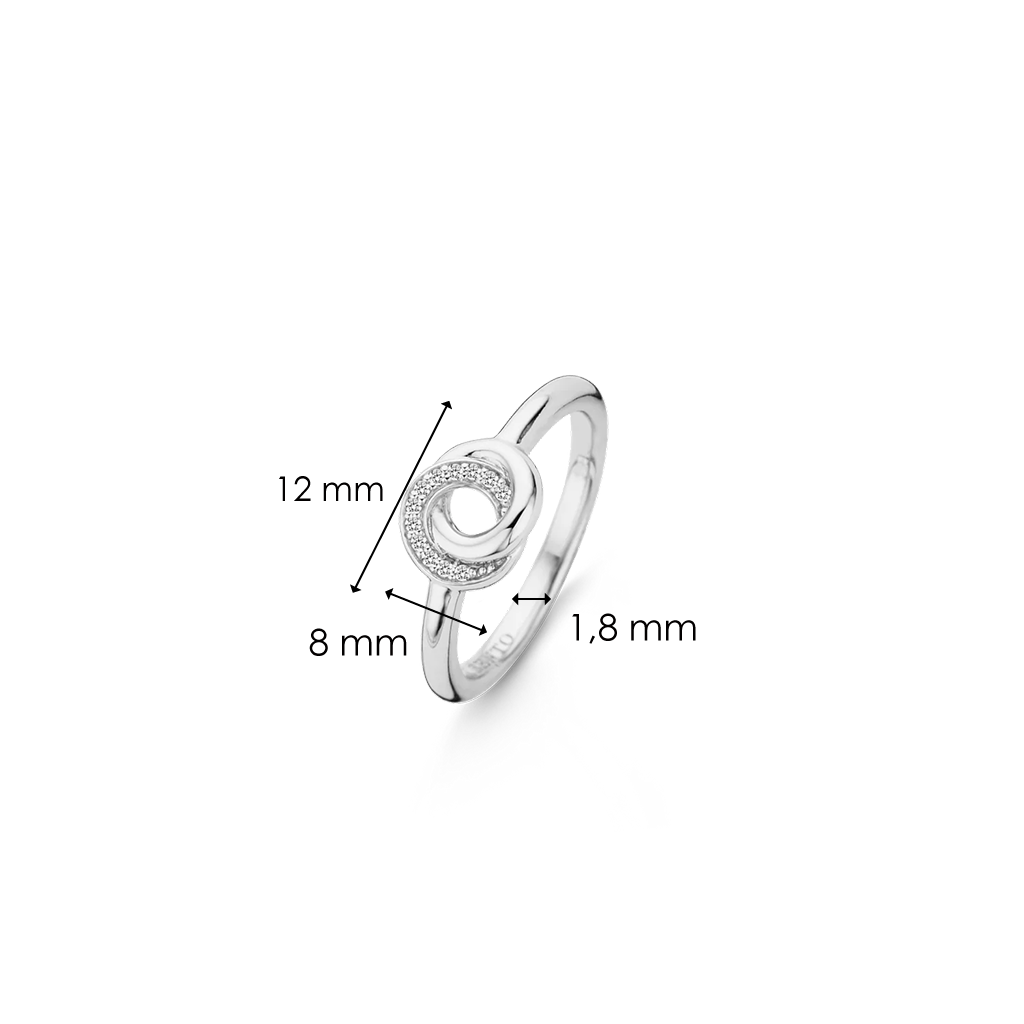 Imagem de um anel de prata de lei 925 banhado a ródio, adornado com zircónias. O anel apresenta um design circular central com um diâmetro de 8 mm, cercado por zircónias menores. A banda do anel mede 1,8 mm de largura, e a largura total superior do anel é de 12 mm. 