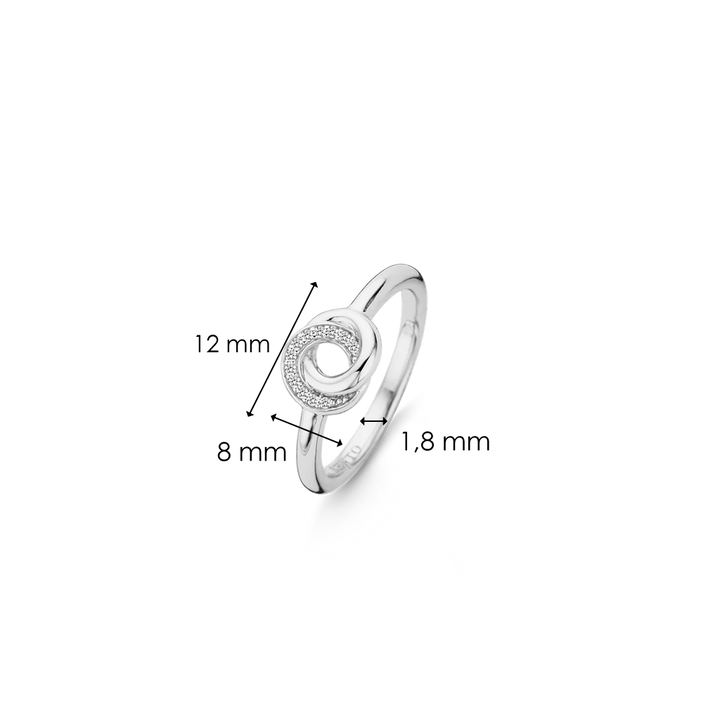 Imagem de um anel de prata de lei 925 banhado a ródio, adornado com zircónias. O anel apresenta um design circular central com um diâmetro de 8 mm, cercado por zircónias menores. A banda do anel mede 1,8 mm de largura, e a largura total superior do anel é de 12 mm. 