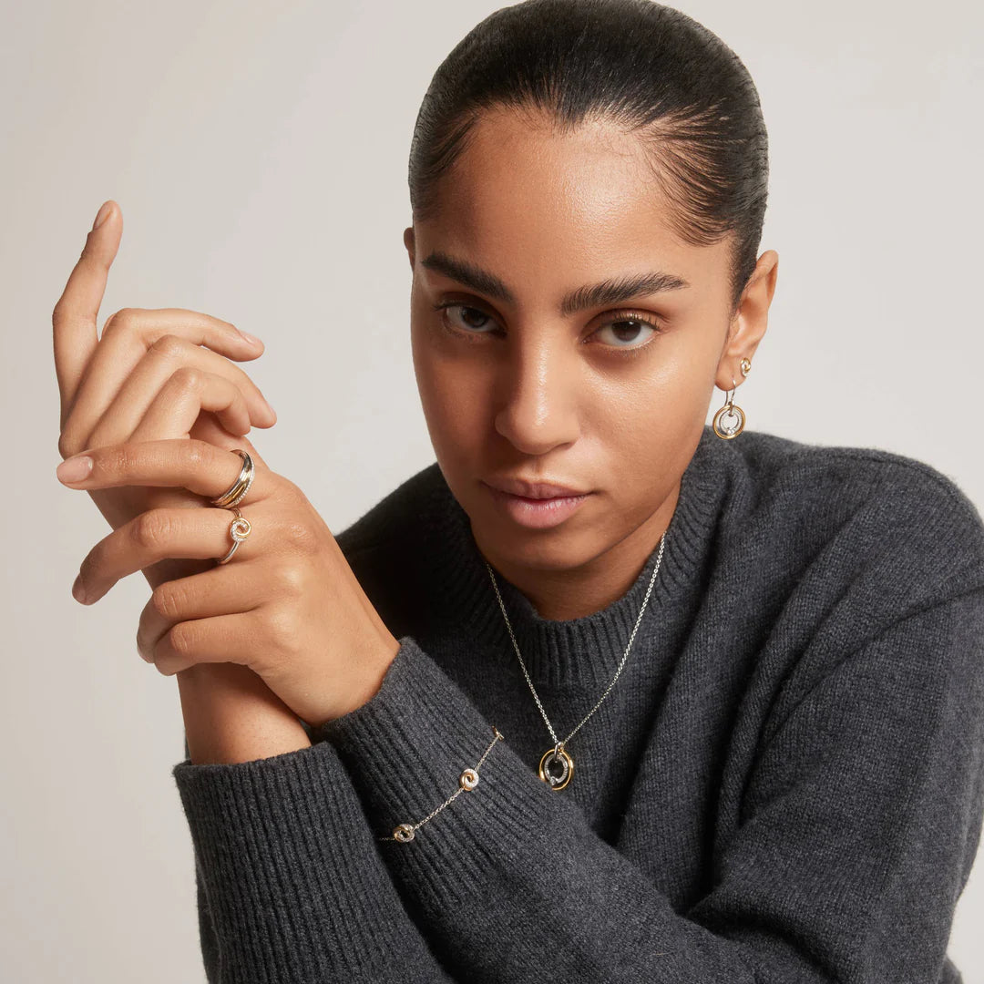 Senhora com o Anel Ti Sento - Milano Prata 925 triplo com uma argola prateada, outra dourada e a outra prateada com zircónias