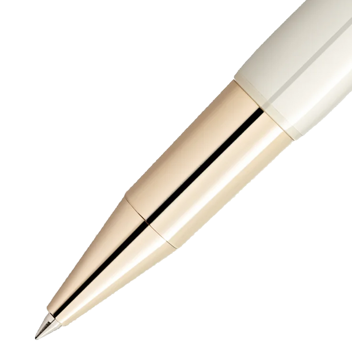 Close-up de uma caneta de resina com um design elegante. A caneta tem um acabamento brilhante e apresenta uma combinação de cores creme e dourado metálico, separadas por uma linha preta fina onde a tampa encontra o corpo. A ponta da caneta é de cor prata, indicando que provavelmente é uma caneta esferográfica