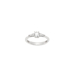 Um anel de noivado de ouro branco com um único diamante de corte redondo preso por um ajuste minimalista de estilo barra numa banda simples.