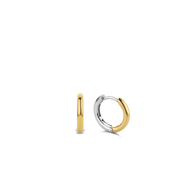 Imagem de um par de argolas feitas à mão, com base em prata e banhadas a ouro. O design é simples e elegante, com um acabamento liso e um mecanismo de fecho sem emendas, refletindo a habilidade artesanal envolvida na sua criação.
