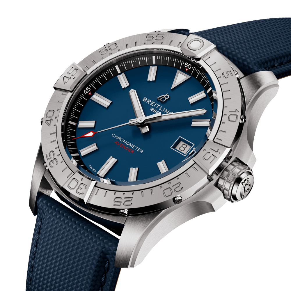 Uma imagem em close-up de um cronômetro Breitling. O relógio tem um mostrador azul com ponteiros e marcadores de hora em tom de prata, e uma janela de data na posição das 3 horas. Possui uma caixa de aço inoxidável com numerais gravados na moldura e está preso a uma pulseira de borracha texturizada azul. O ponteiro dos segundos é vermelho, adicionando um contraste ao esquema de cores azul e prata.