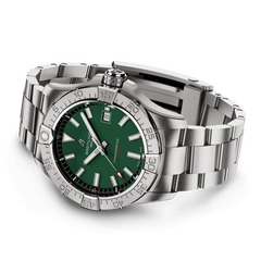 Um relógio de luxo com uma pulseira e caixa de aço inoxidável. O relógio apresenta um mostrador verde com ponteiros e marcadores de hora luminescentes, uma janela de data na posição das 3 horas, e uma moldura rotativa com marcadores de minutos. A manufatura sugere que é um relógio de alta qualidade e precisão.