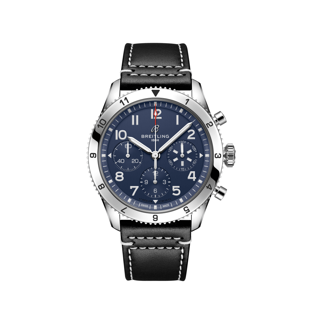 Relógio Breitling com mostrador azul, detalhes em branco e prata, três submostradores e janela de data entre as posições 4 e 5 horas. A caixa é de aço inoxidável com aro giratório marcado de 0 a 60. O relógio possui uma pulseira de couro bovino preta com costura branca.
