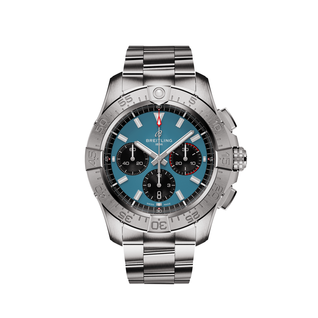 m relógio de pulso Breitling com uma pulseira de aço inoxidável. O relógio apresenta um mostrador preto com três mostradores menores, marcadores de hora e ponteiros em tom de prata, e uma janela de data entre as 4 e 5 horas. A moldura é marcada com indicadores de minutos de 0 a 15 em azul e o resto em preto. O nome da marca ‘Breitling’ é visível no topo do mostrador do relógio.