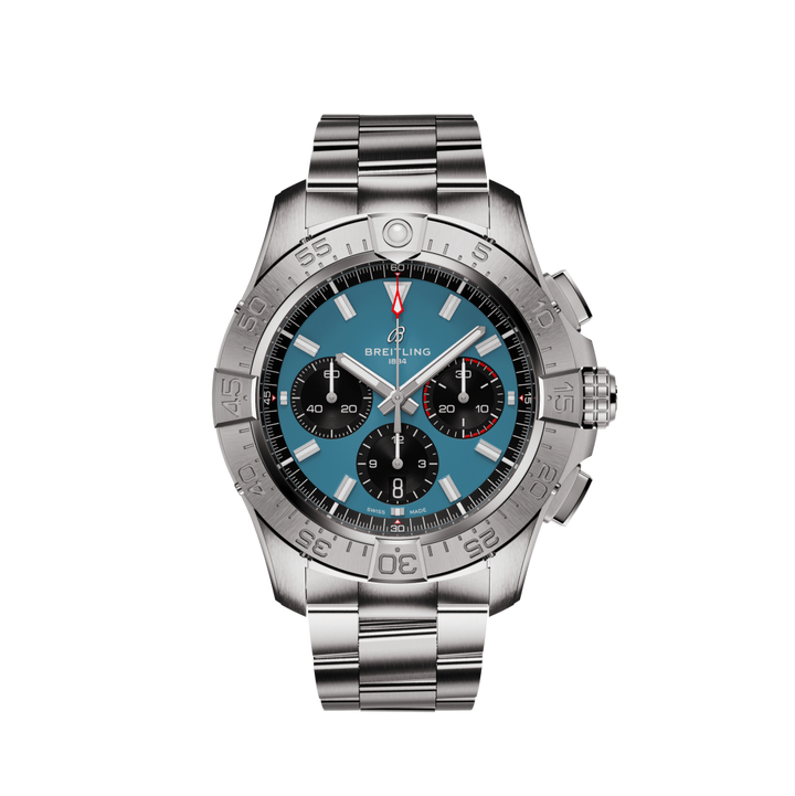 m relógio de pulso Breitling com uma pulseira de aço inoxidável. O relógio apresenta um mostrador preto com três mostradores menores, marcadores de hora e ponteiros em tom de prata, e uma janela de data entre as 4 e 5 horas. A moldura é marcada com indicadores de minutos de 0 a 15 em azul e o resto em preto. O nome da marca ‘Breitling’ é visível no topo do mostrador do relógio.