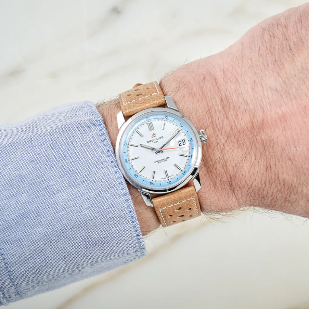 Pulso homem com Relógio Breitling Top Time B31 38mm de caixa prateada, pulseira de pele castanha clara com mostrador branco com rebordo azul