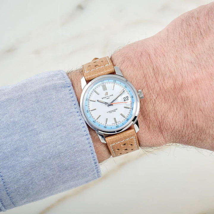 Pulso homem com Relógio Breitling Top Time B31 38mm de caixa prateada, pulseira de pele castanha clara com mostrador branco com rebordo azul