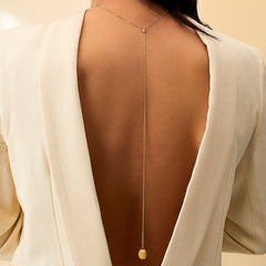 Senhora com o Colar NANIS Dancing Elite dourado com pormenor de união revestido em zircónias com um fio longo e pendente oval no fim, nas costas o mais justo ao pescoço