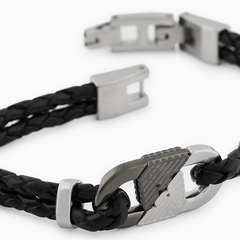 Vista aproximada da peça de aço inoxidável em dois tons e águia cravada no prateado e no prateado escuro da Pulseira Armani ID de pele preta com fecho dobrável de encaixe aberto