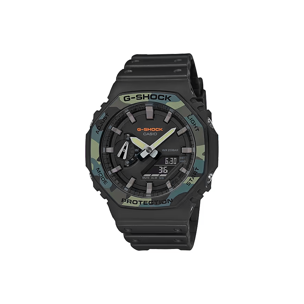 Relógio de pulso G-Shock digital-analógico feito de resina. O relógio tem um esquema de cores preto e cinza escuro com um design robusto, apresentando ponteiros analógicos e displays digitais no mostrador. A hora no display digital marca 6:30, com a etiqueta ‘PROTECTION’ acima, indicando a ênfase da marca na durabilidade. O relógio também mostra outras funções como o dia da semana, indicado por ‘TUE’ no canto superior direito, e segundos exibidos em uma pequena janela perto do centro.