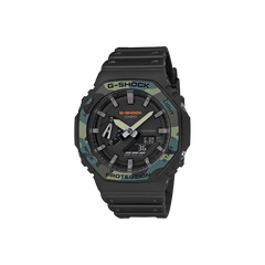 Relógio de pulso G-Shock digital-analógico feito de resina. O relógio tem um esquema de cores preto e cinza escuro com um design robusto, apresentando ponteiros analógicos e displays digitais no mostrador. A hora no display digital marca 6:30, com a etiqueta ‘PROTECTION’ acima, indicando a ênfase da marca na durabilidade. O relógio também mostra outras funções como o dia da semana, indicado por ‘TUE’ no canto superior direito, e segundos exibidos em uma pequena janela perto do centro.