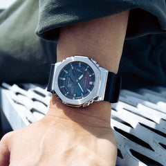 Pulso homem com relógio G-Shock Classic pulseira preta, caixa prateada e mostrador arco-íris