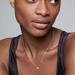 colar de prata banhado a ródio, adornado com pedras de zircónia, da marca Michael Kors. O colar apresenta uma corrente delicada com um pingente de zircónia proeminente que se destaca contra a pele da mulher que o usa