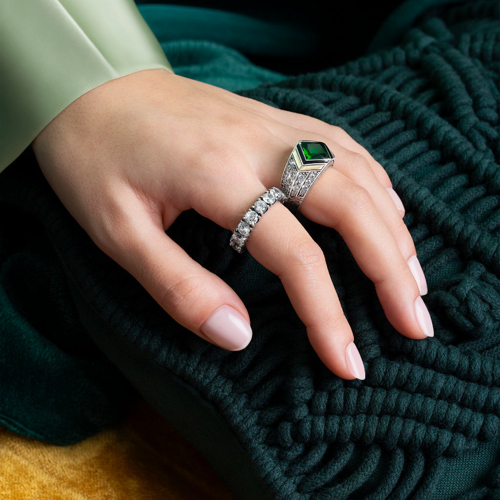 Senhora com Anel TASHI Marrakech coberto de zirónias brancas e quatro divisões (duas douradas e duas pretas) a separar a zircónia verde central. A senhora está também a usar outro anel, forrado em zircónias brancas, modelo Memória