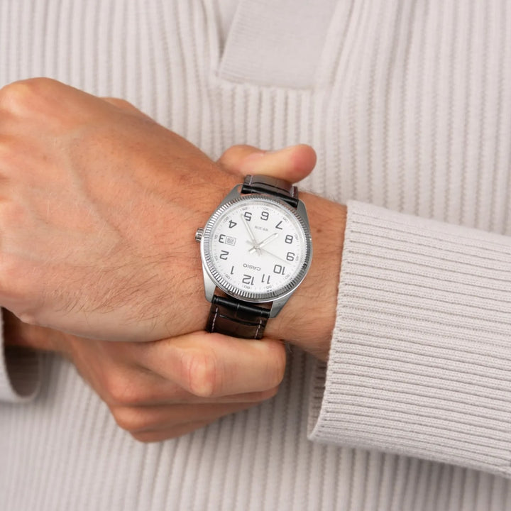 Pulso homem com o relógio Casio Timeless com pulseira couro preta e mostrador branco
