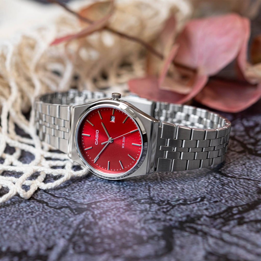 Relógio Timeless prateado com mostrador romano vermelho pousado de lado