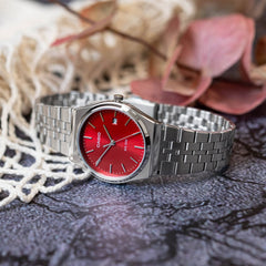 Relógio Timeless prateado com mostrador romano vermelho pousado de lado