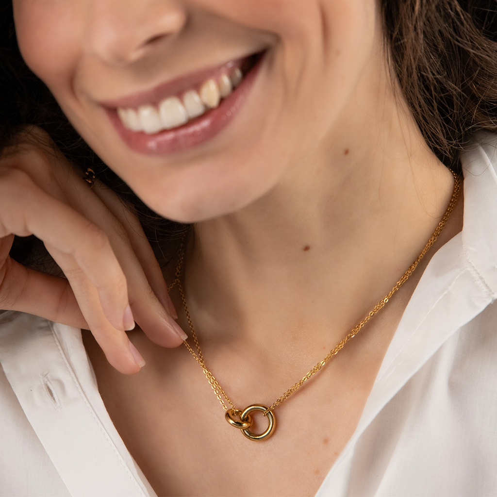 Senhora a usar ao pescoço o Colar One Luminous Circle dourado de malha fina dupla entrançada com duas argolas pendentes