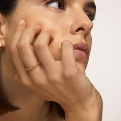 imagem de mulher com queixo pousado na palma da mão. A mulher está séria e contemplativa. No dedo do meio usa o anel one london 33