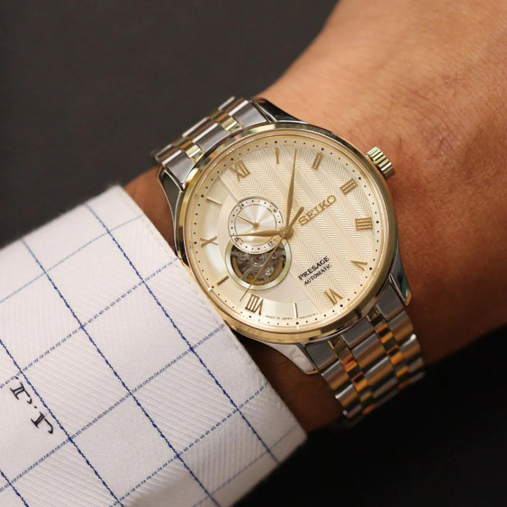 Pulso homem com Relógio Seiko Presage Japanese Garden 41.8mm de pulseira prateada com duas linhas douradas, de caixa e mostrador dourados com indicação de dia da semana e mês