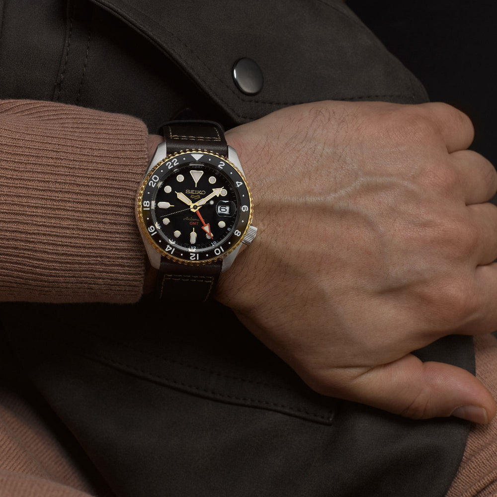 Pulso homem com Relógio Seiko 5 Sports SKX Specialist Style 42.5mm de pulseira pele castanha com caixa prateada e dourada e  mostrador preto com indicação do dia do mês