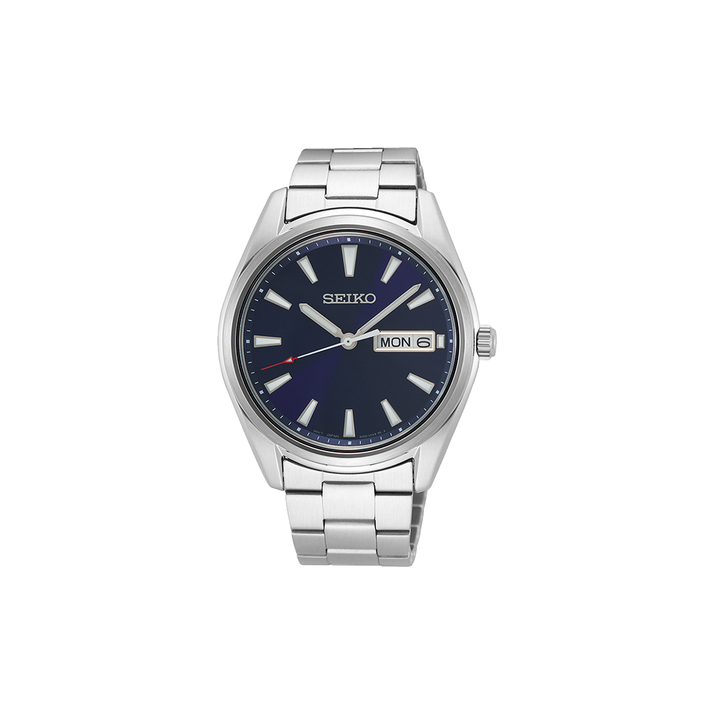 Relógio de pulso Seiko de aço inoxidável com mostrador azul escuro e marcadores prateados. O mostrador exibe o dia da semana na parte superior e a data na parte inferior, ambos próximos à marca das 3 horas. A caixa e a pulseira são de aço polido e escovado, conferindo um visual sofisticado adequado para várias ocasiões.