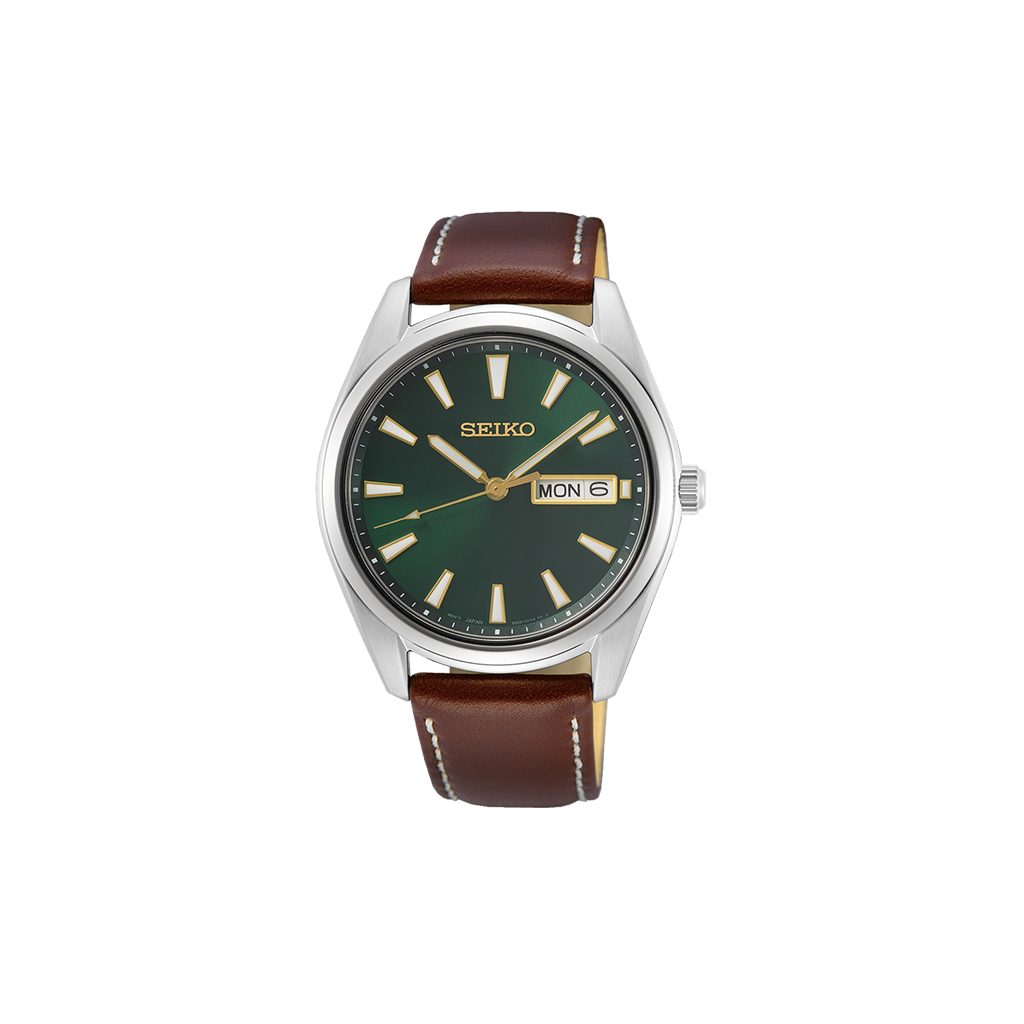 Relógio Seiko com caixa de aço inoxidável e mostrador verde escuro. O relógio possui um visor de dia e data na posição das 3 horas, com ponteiros e marcadores prateados. A pulseira é de couro bovino marrom com costura visível e fecho de fivela, combinando funcionalidade e elegância clássica.
