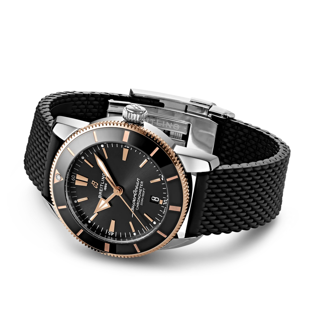 Relógio Breitling Superocean Heritage B20 Automatic 44mm de caixa prateada, pulseira silicone e mostrador pretos com detalhes rosa dourado deitado de lado
