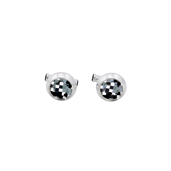 Um par de botões de punho com uma moldura redonda e prateada e um design quadriculado preto e branco no centro. O padrão cria uma ilusão óptica de profundidade tridimensional, assemelhando-se a um tabuleiro de xadrez que se curva para dentro. Os botões de punho estão definidos contra um fundo branco simples, destacando seu design intrincado e acabamento polido.
