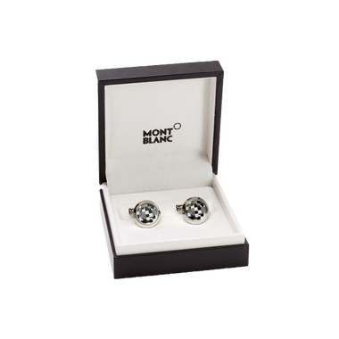 Uma caixa aberta da marca Montblanc contendo um par de botões de punho elegantes. Os botões de punho têm um design circular distinto com um padrão preto e branco contrastante que os destaca. Eles estão colocados nos slots dedicados dentro da caixa, que é marcada com ‘MONTBLANC’ na parte superior do interior. A apresentação em tal embalagem sugere que estes são acessórios de alta qualidade, possivelmente destinados a trajes formais ou como um presente de luxo.