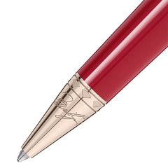 Imagem em close-up de uma esferográfica de resina com um acabamento brilhante vermelho. A caneta tem uma ponta e clipe metálicos na cor dourada, apresentando detalhes e gravações intrincados nos componentes metálicos. O design sugere elegância e uma estética clássica.