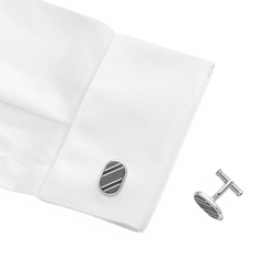 Um par de botões de punho em formato oval com acabamento em prata e um design de uma única listra preta, exibidos no punho de uma camisa social branca. Os botões de punho são elegantes e proporcionam um acessório sutil, mas sofisticado, para o traje formal.