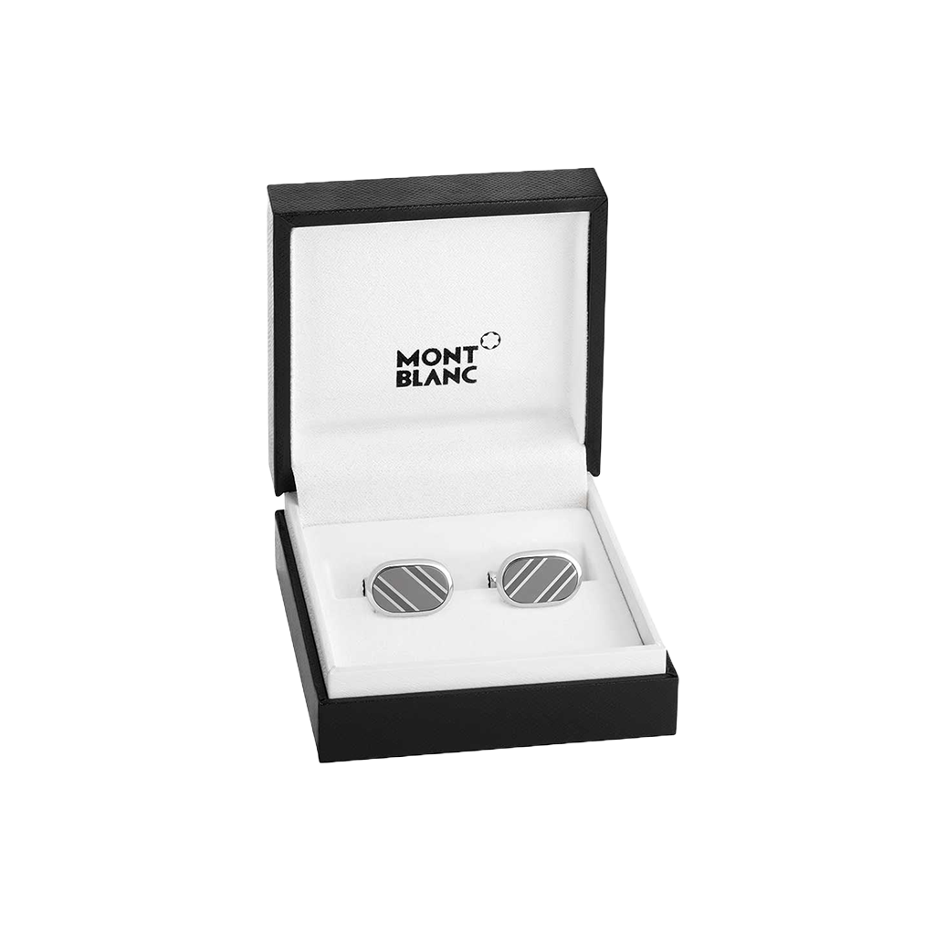 Um par de botões de punho de prata com um design listrado está exibido dentro de uma caixa aberta da marca Mont Blanc. A caixa é preta por fora e branca por dentro, com o logotipo da Mont Blanc impresso na parte superior interior. Os botões de punho estão colocados em um slot dedicado, destacando sua elegância e apelo de luxo