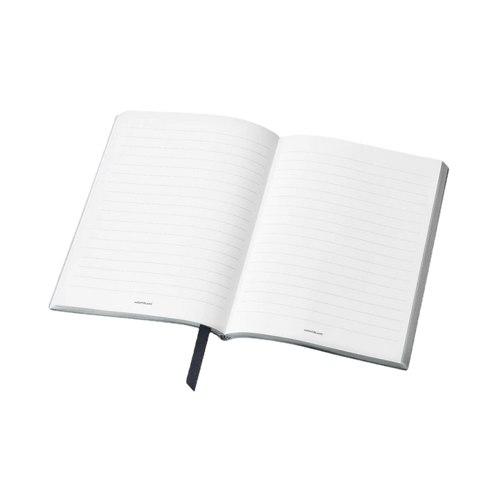 Um caderno de capa dura aberto com páginas pautadas. O caderno está posicionado em um ângulo leve, exibindo uma fita marcadora azul visível na parte inferior central da página. O fundo é branco puro, enfatizando o estado limpo e não utilizado do caderno.