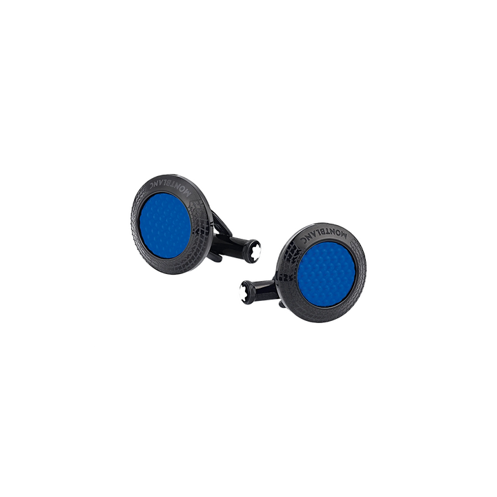 Um par de botões de punho com laca de pedra azul, inseridos numa moldura metálica circular polida. Os botões de punho têm uma superfície texturizada e são exibidos contra um fundo claro e simples, que contrasta com o metal escuro e a cor vibrante azul da laca. O nome da marca é visível na lateral do mecanismo de fixação de cada botão de punho.