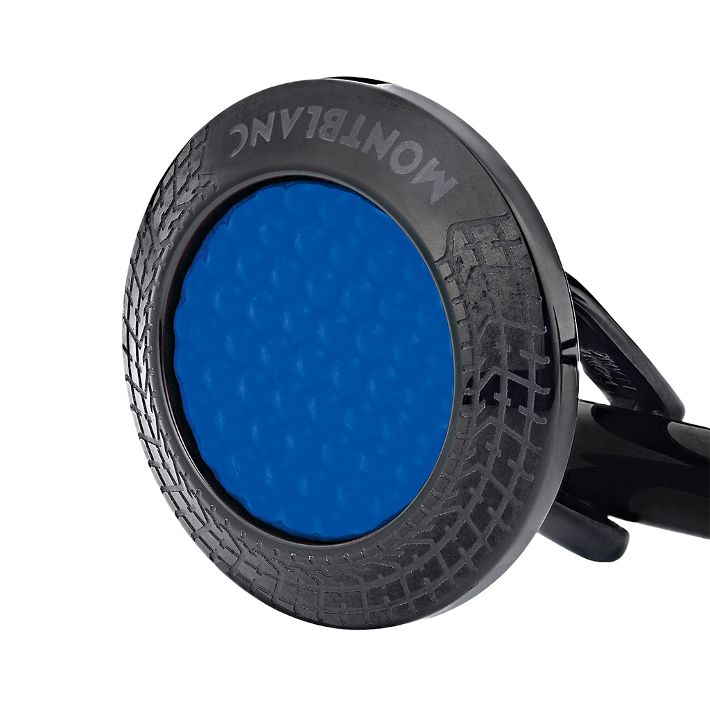 Imagem em close-up de um botão de punho que apresenta uma laca de pedra azul inserida numa moldura metálica circular preta com um padrão intrincado de banda de rodagem de pneu. A marca ‘MONTBLANC’ está gravada ao longo da borda superior da moldura metálica. O fundo é branco, destacando o contraste e os detalhes do design do botão de punho