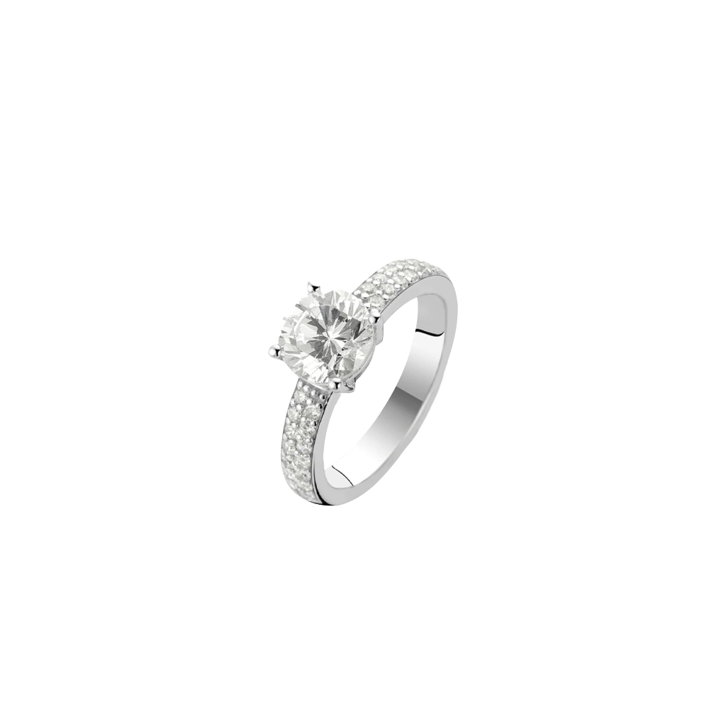 Imagem de um anel de prata banhado a ródio, apresentando uma grande pedra central de zircônia fixada em uma cravação. A banda do anel é adornada com pedras de zircônia menores, fixadas em pavê que a circundam, adicionando ao brilho e elegância da peça. O fundo é branco simples, enfatizando o design e a habilidade do anel.