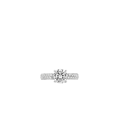 Imagem da vista de cima de um anel de prata banhado a ródio, apresentando uma grande pedra central de zircônia fixada em uma cravação. A banda do anel é adornada com pedras de zircônia menores, fixadas em pavê que a circundam, adicionando ao brilho e elegância da peça. O fundo é branco simples, enfatizando o design e a habilidade do anel.