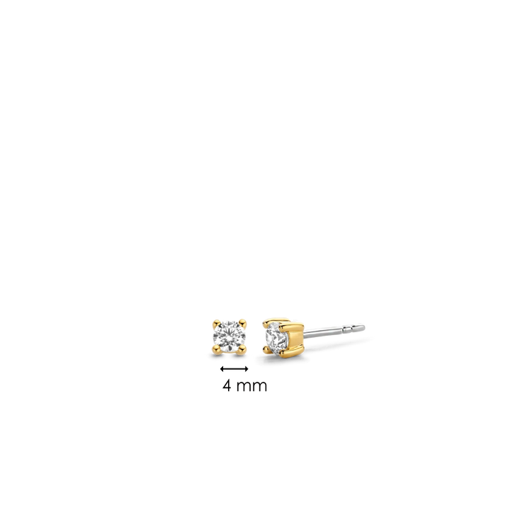 Um par de brincos Ti Sento de prata banhada a ouro, apresentando um design simples, mas elegante. Cada brinco exibe uma única pedra de zircónia redonda fixada num bisel banhado a ouro. A imagem fornece uma referência de medida indicando que a pedra de zircónia tem 4 mm de diâmetro, enfatizando o tamanho delicado destes acessórios refinados.