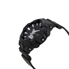 Relógio de pulso Casio G-Shock com bracelete de resina preta e design robusto. O mostrador combina displays analógicos e digitais, com ponteiros prateados e marcadores de hora sobre um fundo preto. O bisel é marcado com indicadores de minutos e a inscrição “SHOCK RESIST”. Funções adicionais incluem exibição de dia e data, além de configurações de alarme visíveis no mostrador.