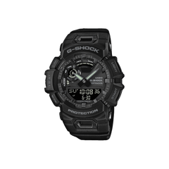 Relógio Casio G-Shock de resina preta com display digital-analógico. O design é robusto, com vários botões e detalhes texturizados nas laterais. A tela digital mostra a hora 10:08:36 e a data 6-30, indicando 30 de junho. Os ponteiros do relógio analógico estão próximos das marcas de 10 e 2 horas. A palavra ‘PROTECTION’ está destacada na parte inferior do mostrador, enfatizando sua construção durável