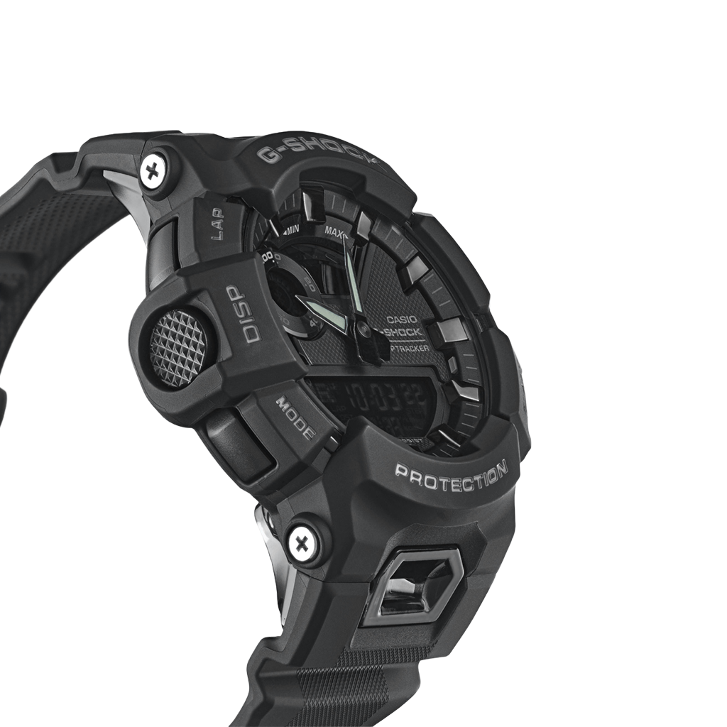 relógio Casio G-Shock de resina preta. O design é robusto, com múltiplos botões e detalhes texturizados nas laterais. O display é digital, com indicadores para vários modos como alarme, cronômetro e hora mundial. A palavra ‘PROTECTION’ está destacada acima da tela digital, enfatizando a durabilidade do relógio. A pulseira parece ser feita de um material durável, provavelmente borracha ou um material sintético similar, adequado para uso ativo ou ao ar livre.