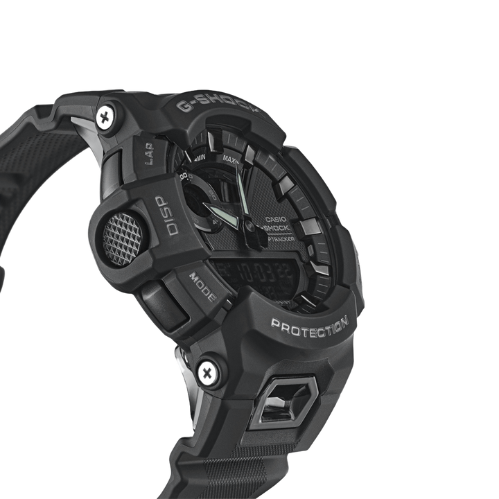 relógio Casio G-Shock de resina preta. O design é robusto, com múltiplos botões e detalhes texturizados nas laterais. O display é digital, com indicadores para vários modos como alarme, cronômetro e hora mundial. A palavra ‘PROTECTION’ está destacada acima da tela digital, enfatizando a durabilidade do relógio. A pulseira parece ser feita de um material durável, provavelmente borracha ou um material sintético similar, adequado para uso ativo ou ao ar livre.