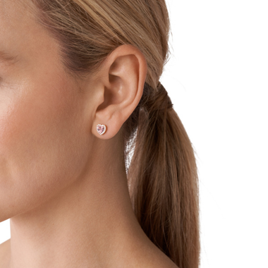 Close-up de um perfil de uma mulher, focando na orelha e numa parte do cabelo. A orelha está adornada com um brinco redondo e cintilante. O cabelo é castanho claro, puxado para trás num rabo de cavalo arrumado. Não há rosto ou outras partes do corpo visíveis devido à área desfocada que cobre parte da imagem.