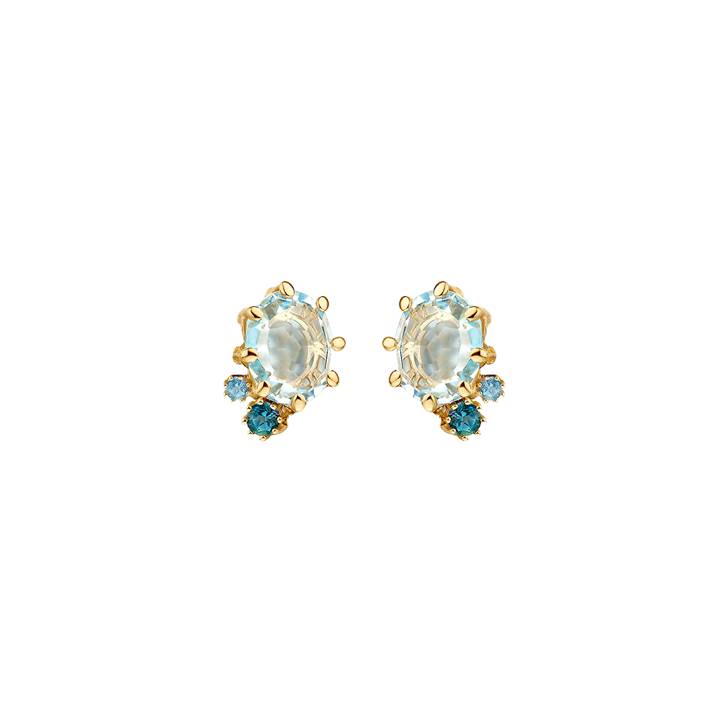 Par de brincos de ouro com um Topázio Azul Londres oval no centro, rodeado por delicadas garras de ouro. A metade inferior de cada brinco é adornada com pequenas pedras de Topázio Azul redondas, realçando o design elegante e as vibrantes tonalidades azuis.