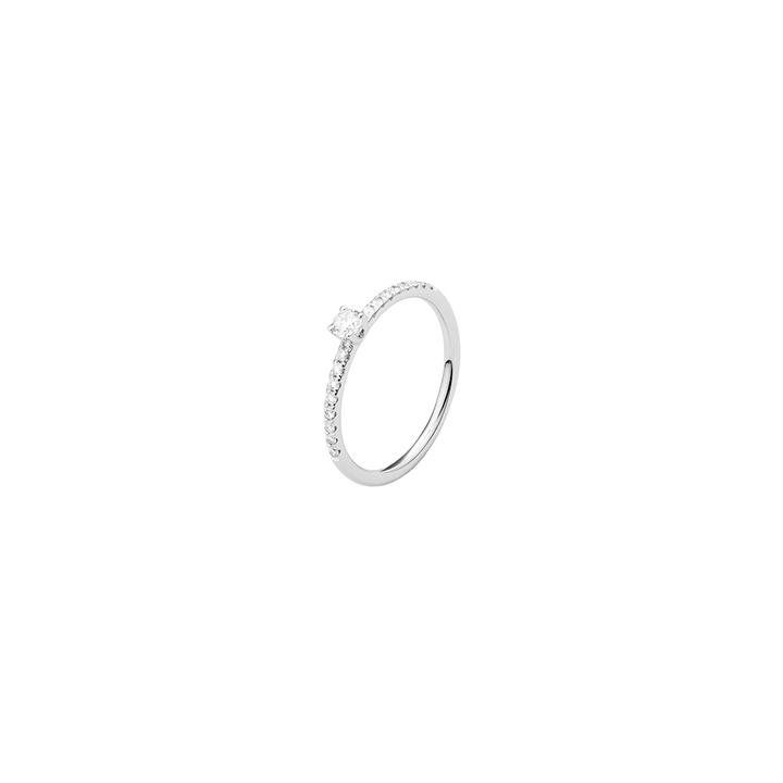 Um anel de cor prateada com uma banda fina, adornado com pequenos diamantes que circundam metade da banda. O anel apresenta um diamante solitário proeminente montado no topo em uma configuração de garra.