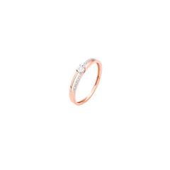 Uma imagem em close-up de um anel de ouro rosé, exibindo uma banda esbelta com um diamante redondo e claro no centro. O diamante é fixado por quatro garras e é ladeado de cada lado por diamantes menores, adicionando um brilho extra ao design sofisticado.